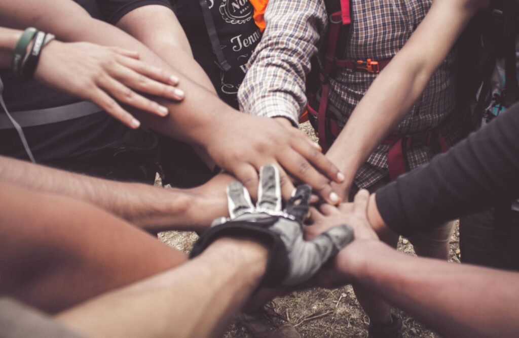 A group of diverse individuals join hands for teamwork in West Java, Indonesia.